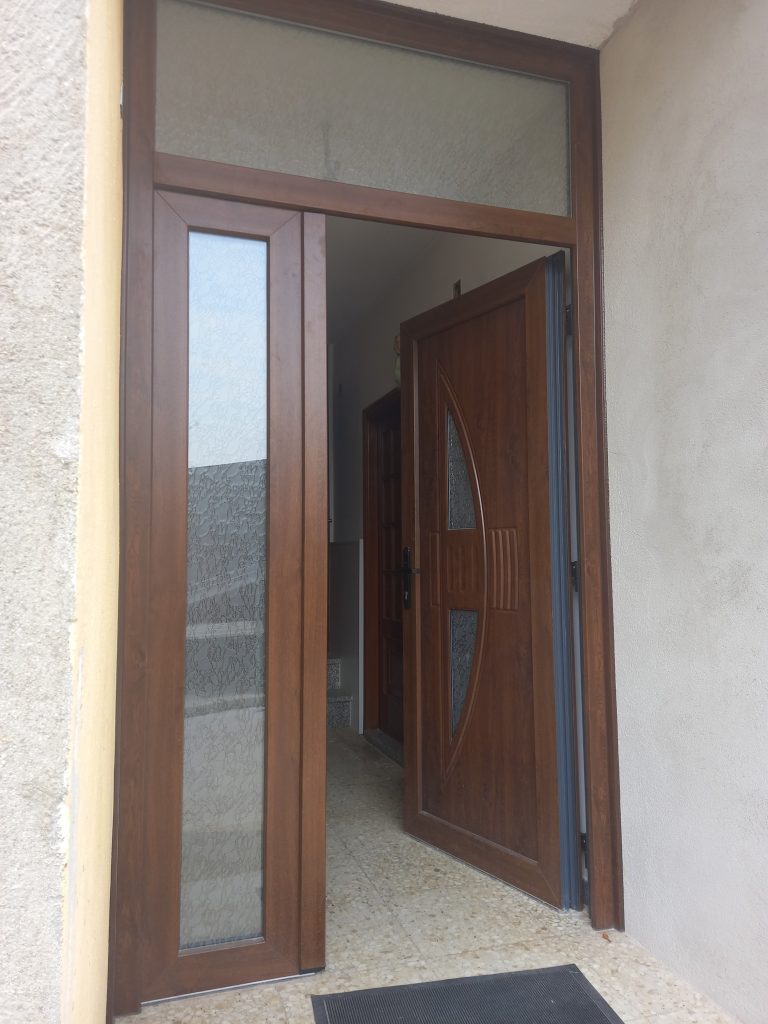 Puerta entrada PVC dos hojas con panel y fijo superior con vidrio delta